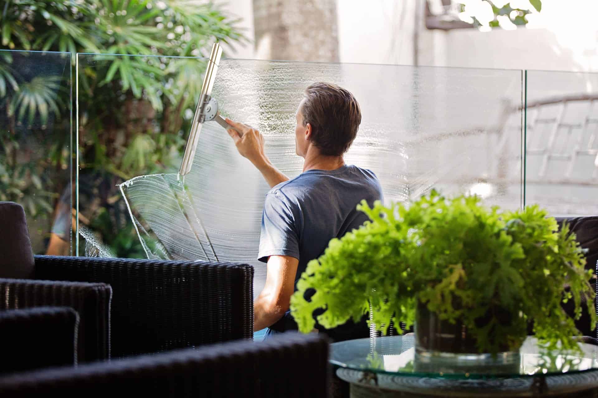 Image of a man using a squeegee to wipe down a window.