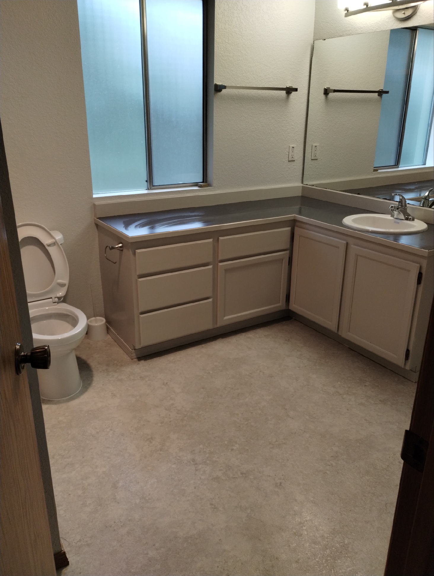 A spotless bathroom, including toilet, l-shaped countertop, sink and mirror,  to help illustrate Spring Cleaning Checklist.