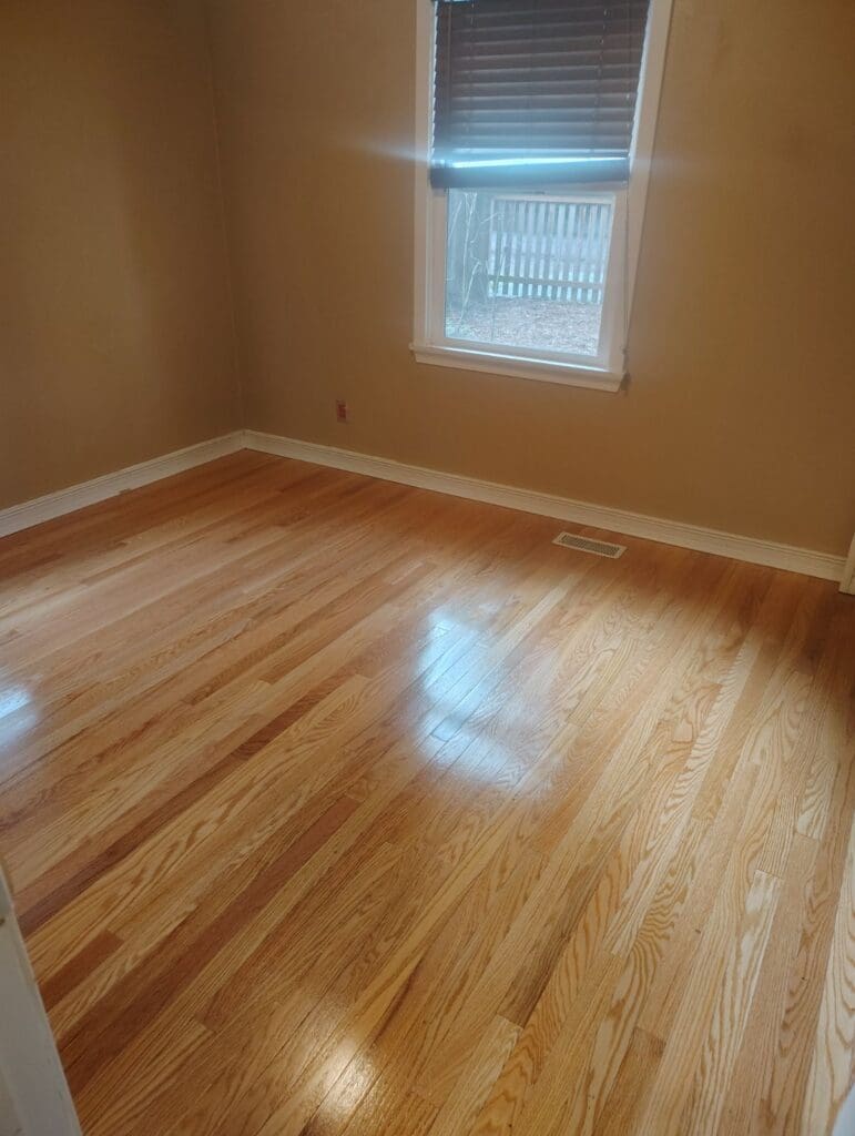 An empty bedroom with shiny hardwood floors to illustrate bedroom cleaning services