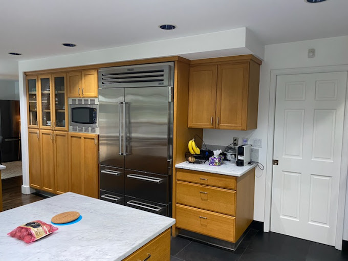 A clean kitchen with stainless steel refrigerator, an island, and cabinetry to help illustrate pre-vacation cleaning checklist.