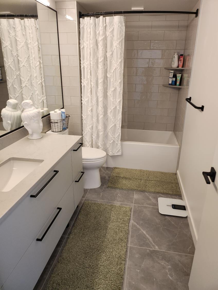 A newly cleaned and fresh bathroom with single vanity, toilet, and tub/shower combo with open curtain