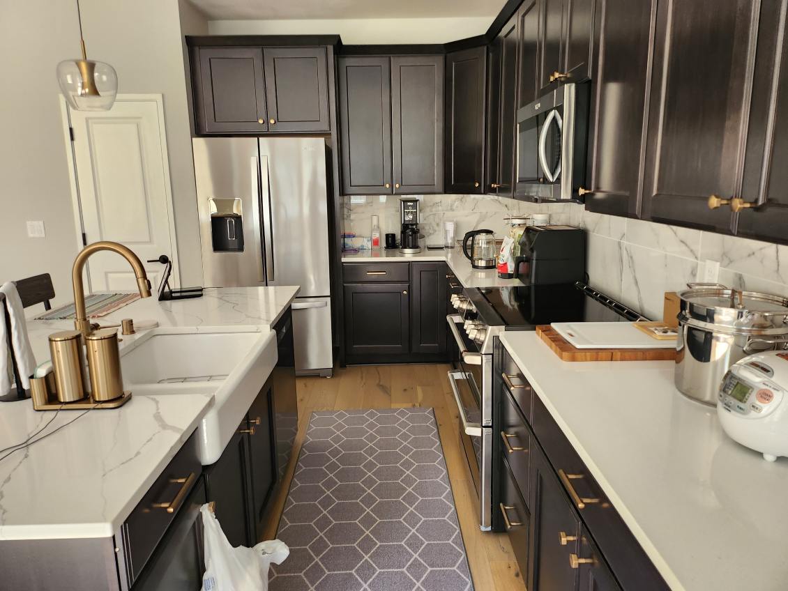 A clean kitchen with brown cabinets and white countertops.