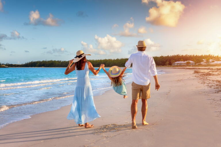 A happy family in walks hand in hand down a tropical beach during sunset tme and enjoys their summer vacation time to illustrate pre-vacation cleaning checklist